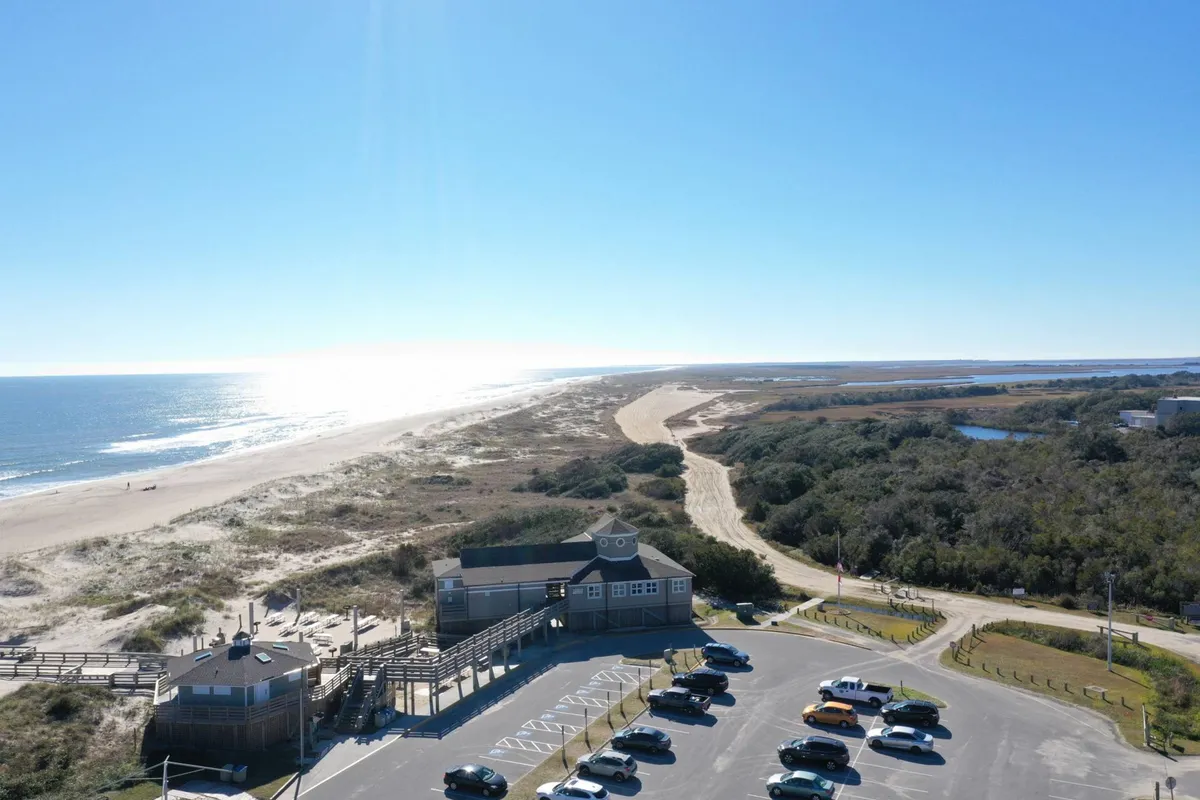 An inviting, sunlit view of the ocean and sandy beach with room for families to spread out. The setting is ideal for sunbathing, beach walks, and relaxing by the water, while children play and explore the shoreline.